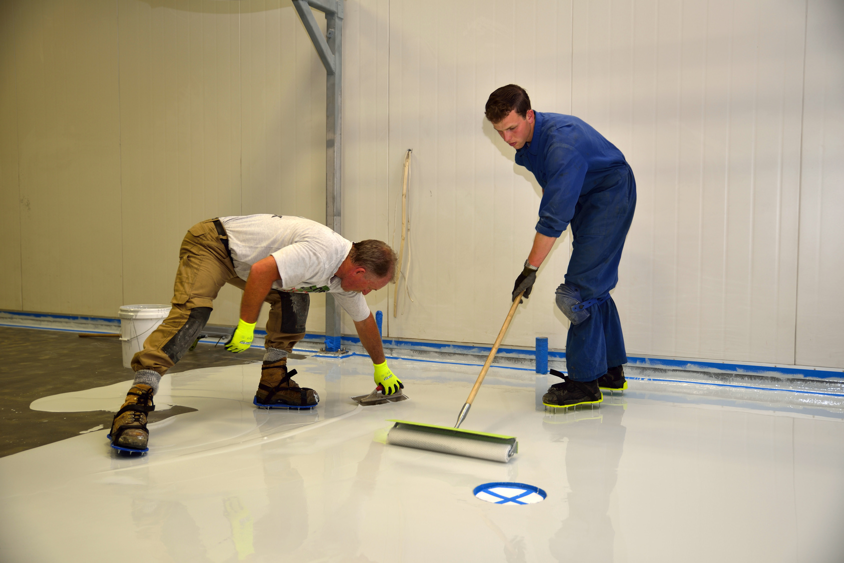 tradesman applying epoxy product to floor of an industrial building